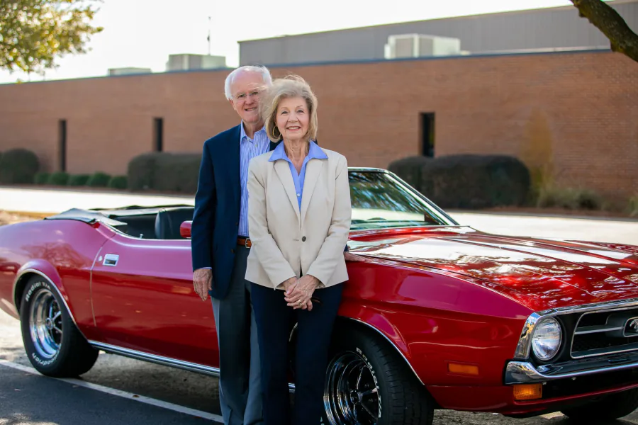 Bill and Norma Monroe standing together beside a red convertible outside Florence Baptist Temple