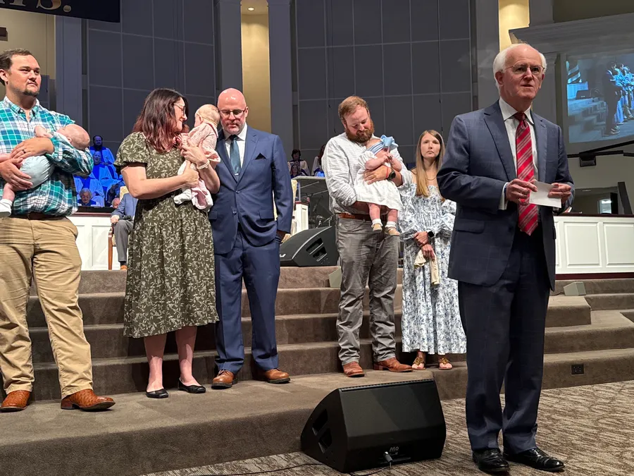 Pastor Bill Monroe standing with families during a baby dedication