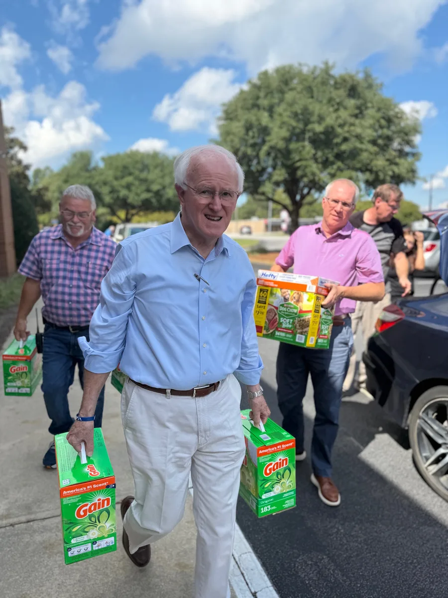 Pastor Bill Monroe carrying boxes of donated household supplies with church members