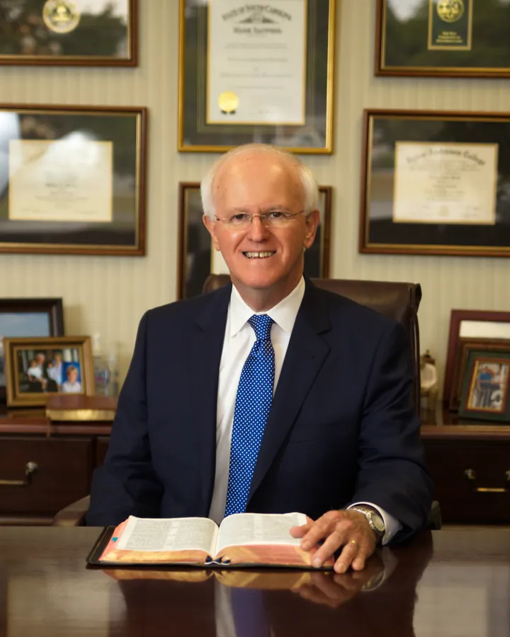 Pastor Bill Monroe seated at his desk with an open Bible