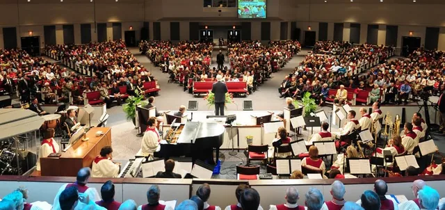 Pastor Bill Monroe seen from behind while addressing a full Florence Baptist Temple auditorium