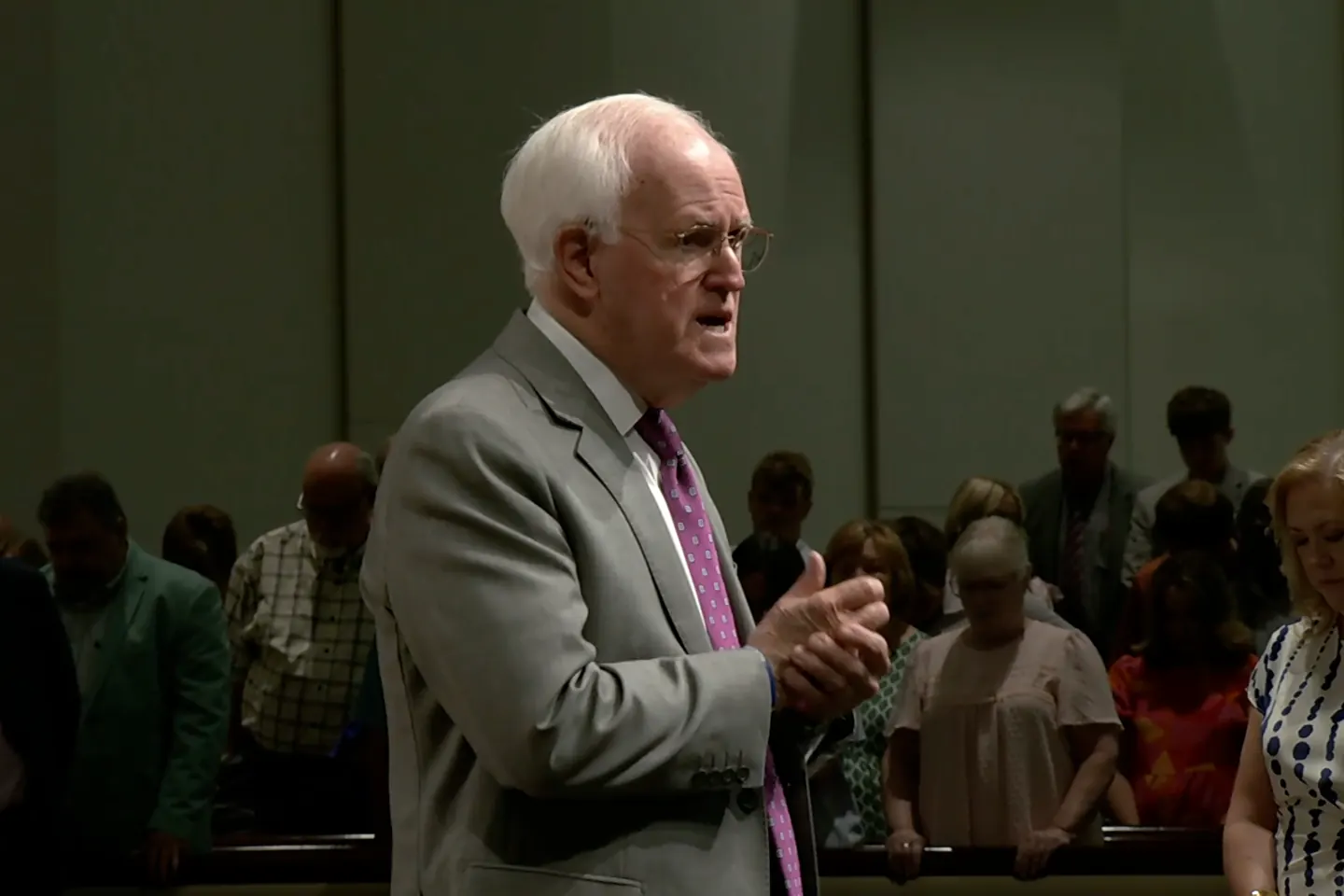 Pastor Bill Monroe preaching among people in the congregation